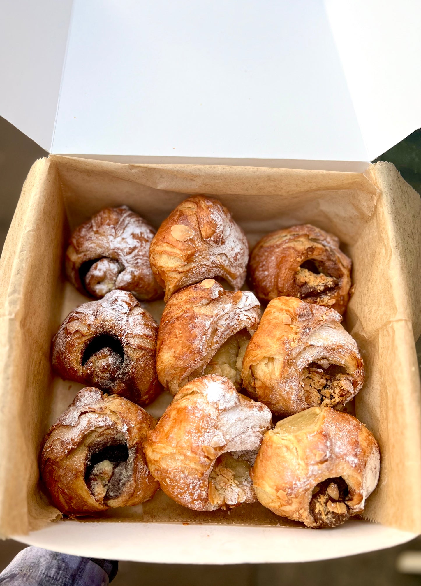 Freshly baked pastries from the Classic Scrolls Box by Pulp, showcasing flaky almond, cinnamon, and Nutella & almond scrolls in a stylish takeaway box.