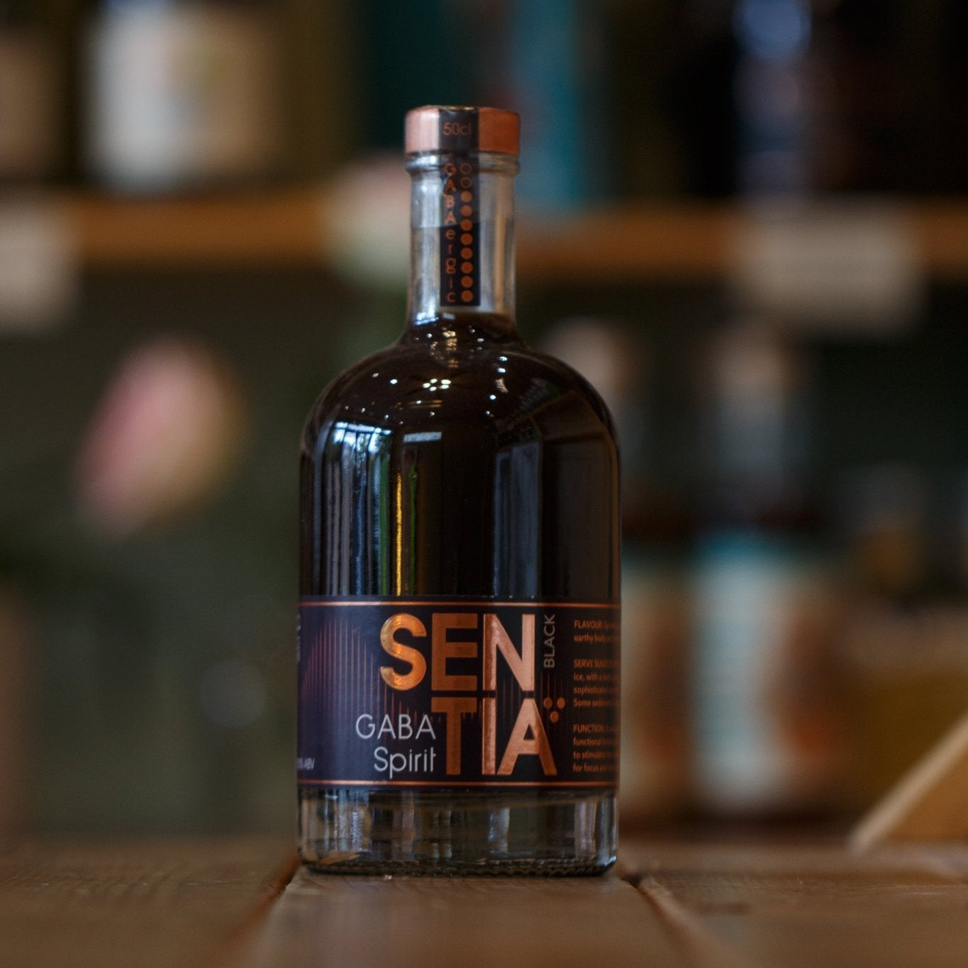 Bottle of Sentia Black on a wooden surface with a blurred background