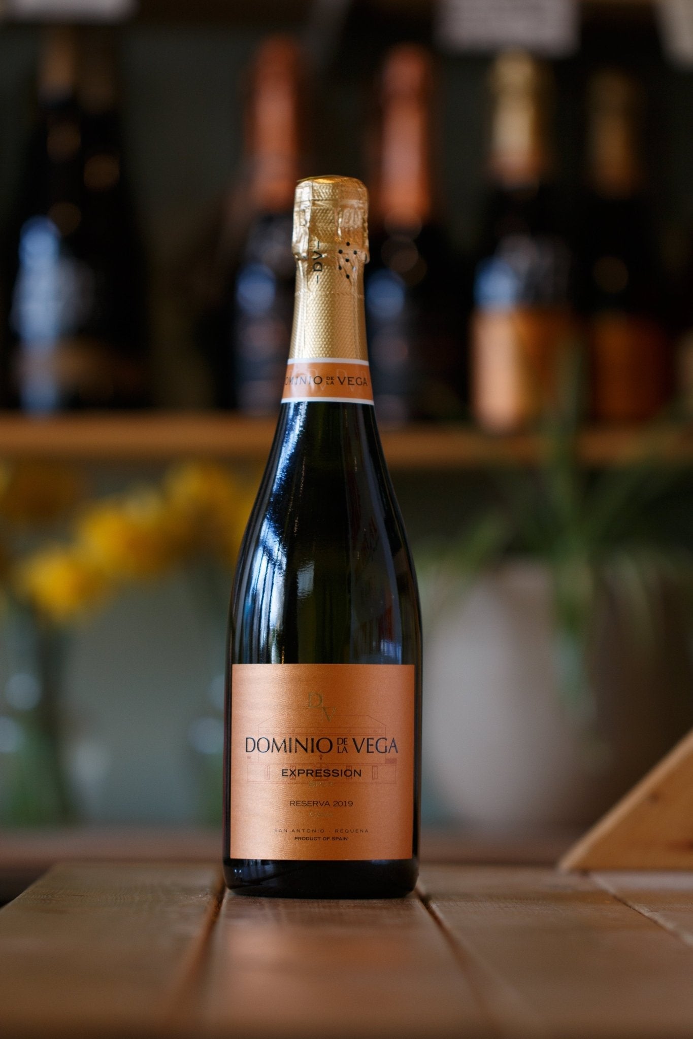 Cava Reserva 2019 from Dominio de la Vega displayed elegantly on a wooden table in a warm setting, showcasing the sparkling wine's refined bottle design.