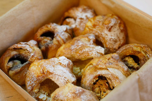 Delicious assortment of pastries from the Classic Scrolls Box by Pulp, featuring hand-rolled almond, cinnamon, and Nutella & almond scrolls nestled in a natural box.