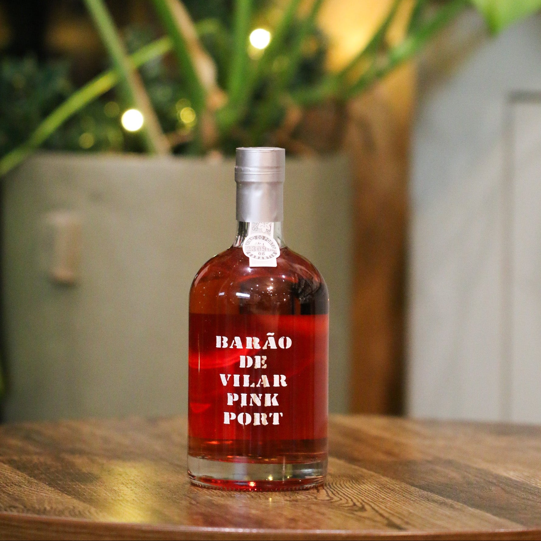 Bottle of Barão de Vilar Pink Port on a wooden table with plants in the background
