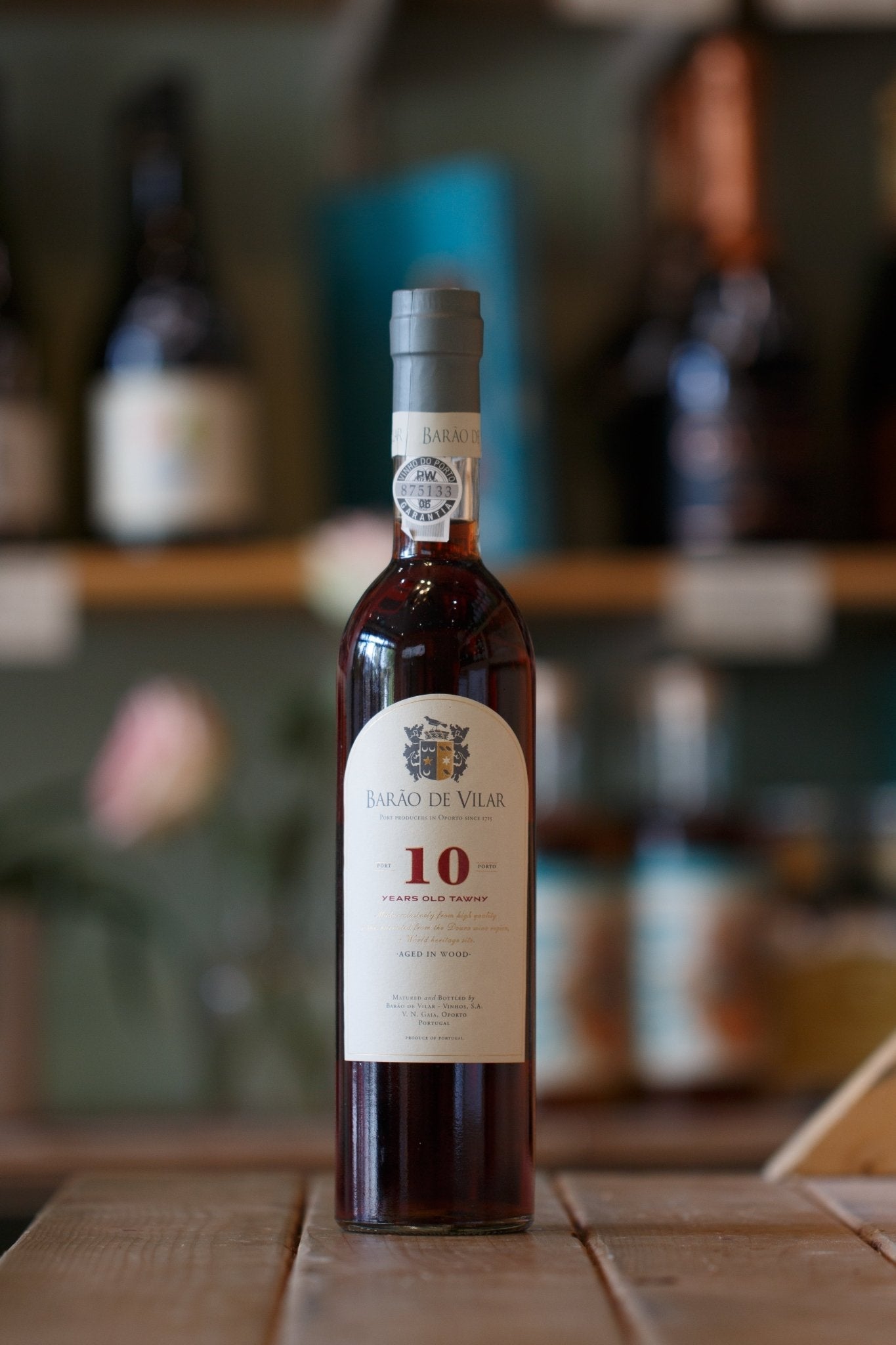 Barão De Vilar 10-Year Tawny Port bottle displayed on a wooden table, showcasing its rich, complex flavor. Perfect for pairing with savory foods like nuts and cheeses.