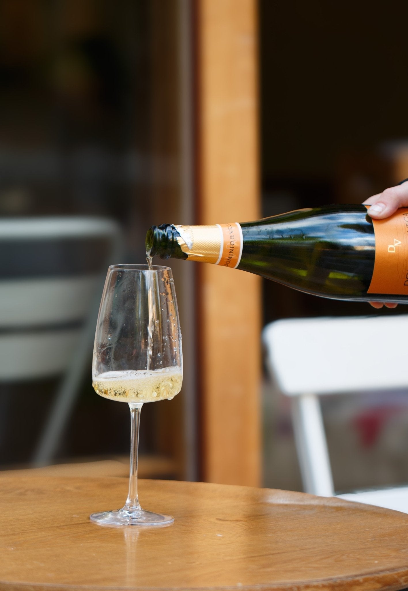 Pouring Cava Reserva 2019 from Dominio de la Vega into a glass, highlighting the sparkling bubbles and vibrant colour in a casual outdoor setting.