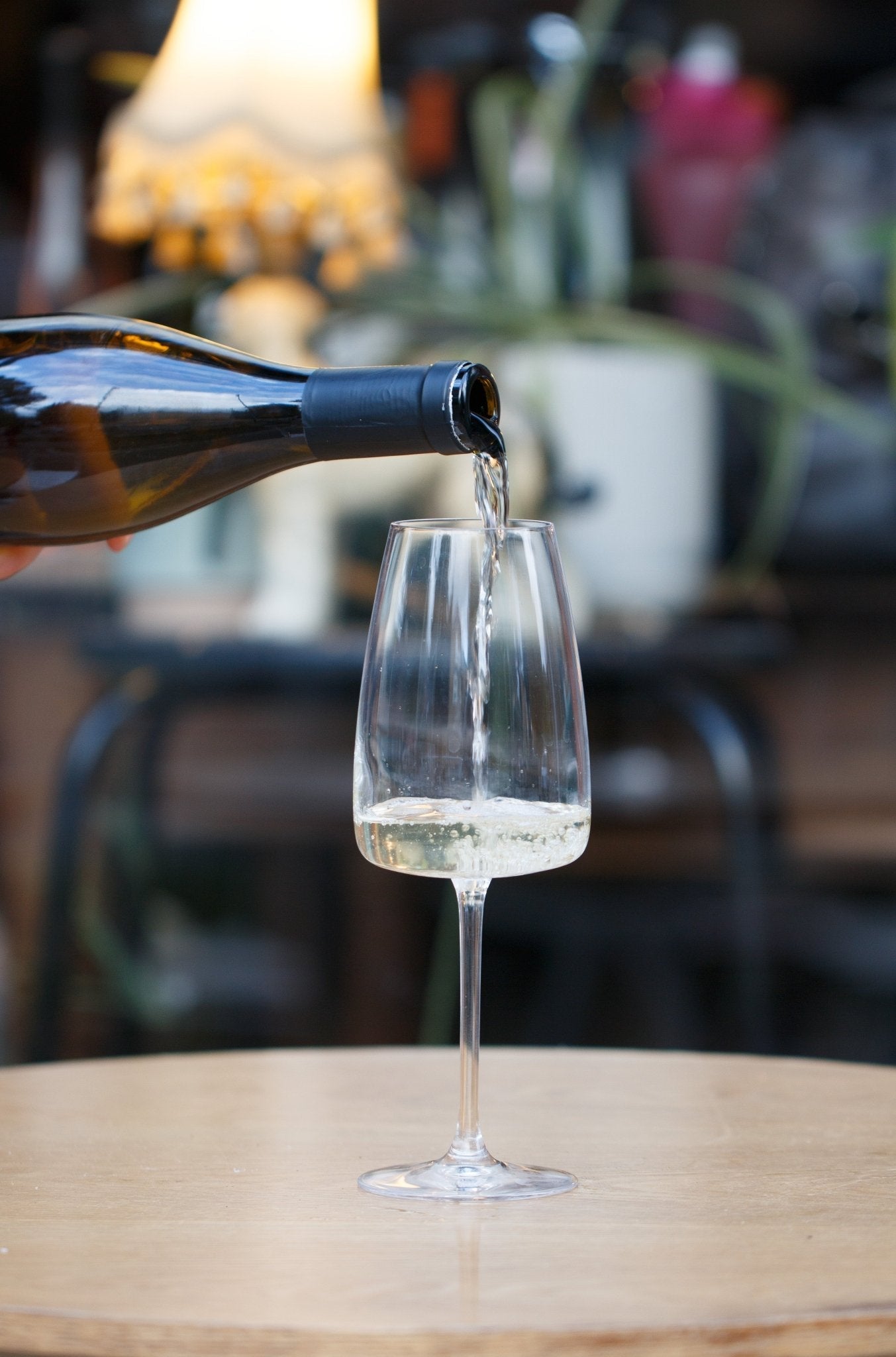 Pouring a glass of La Clef Du Récit Sancerre 2023 by Anthony Girard, demonstrating the vibrant organic Sauvignon Blanc from the Loire Valley, France, set against a rustic table.