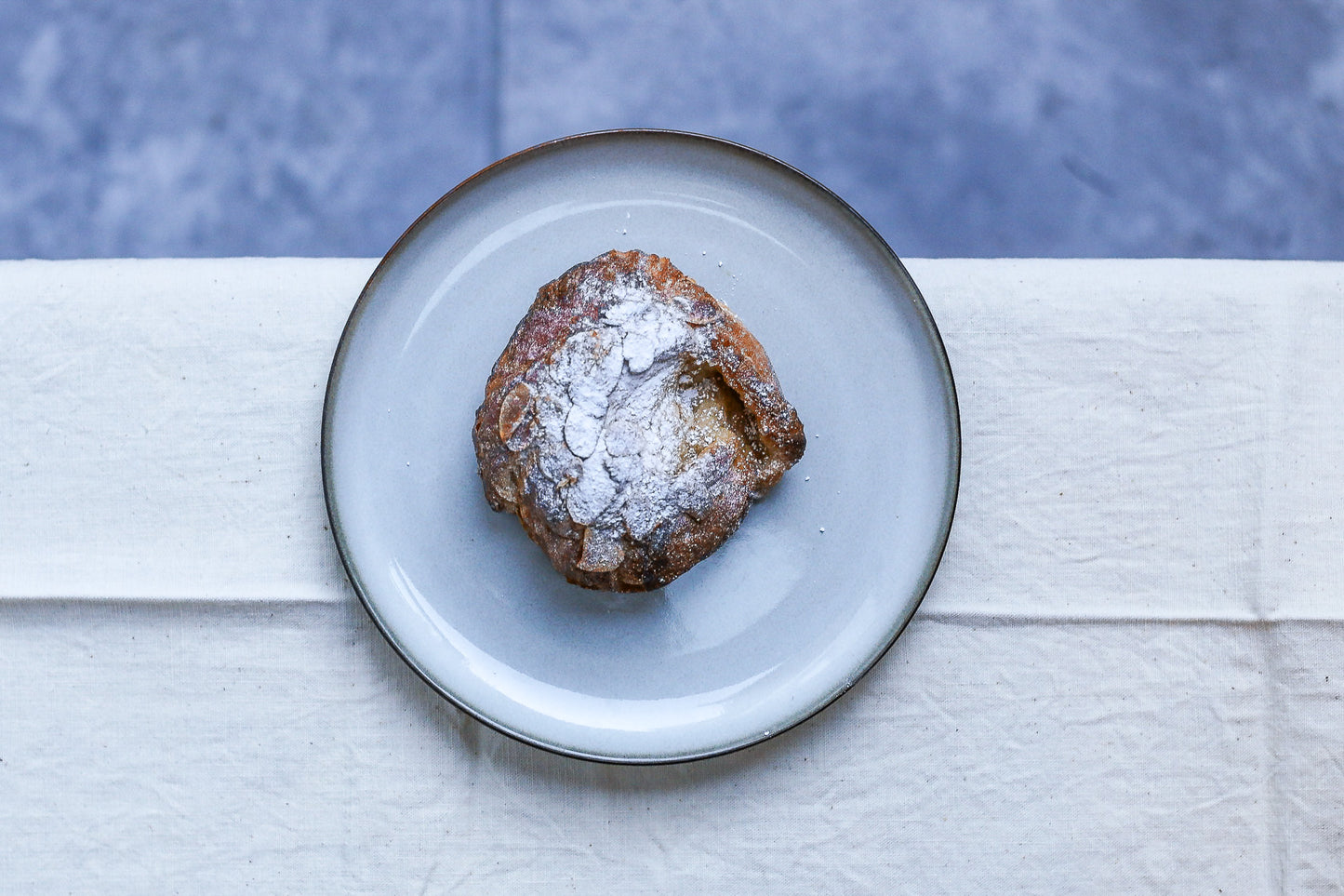Pastry dusted with powdered sugar on a light blue plate against a white and blue striped background