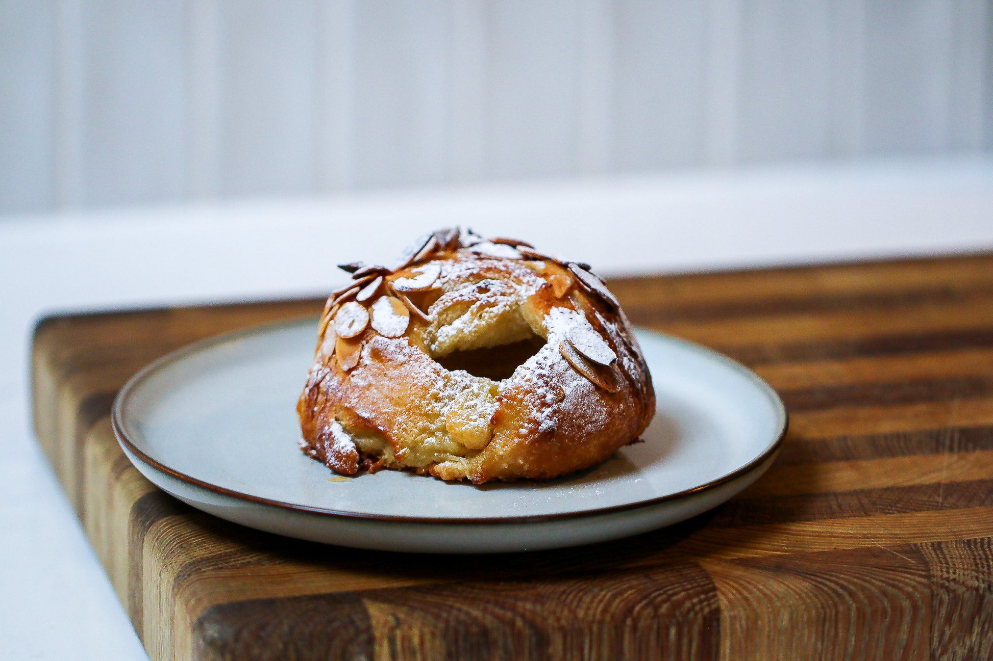 Pastry on a white plate with a wooden cutting board underneath