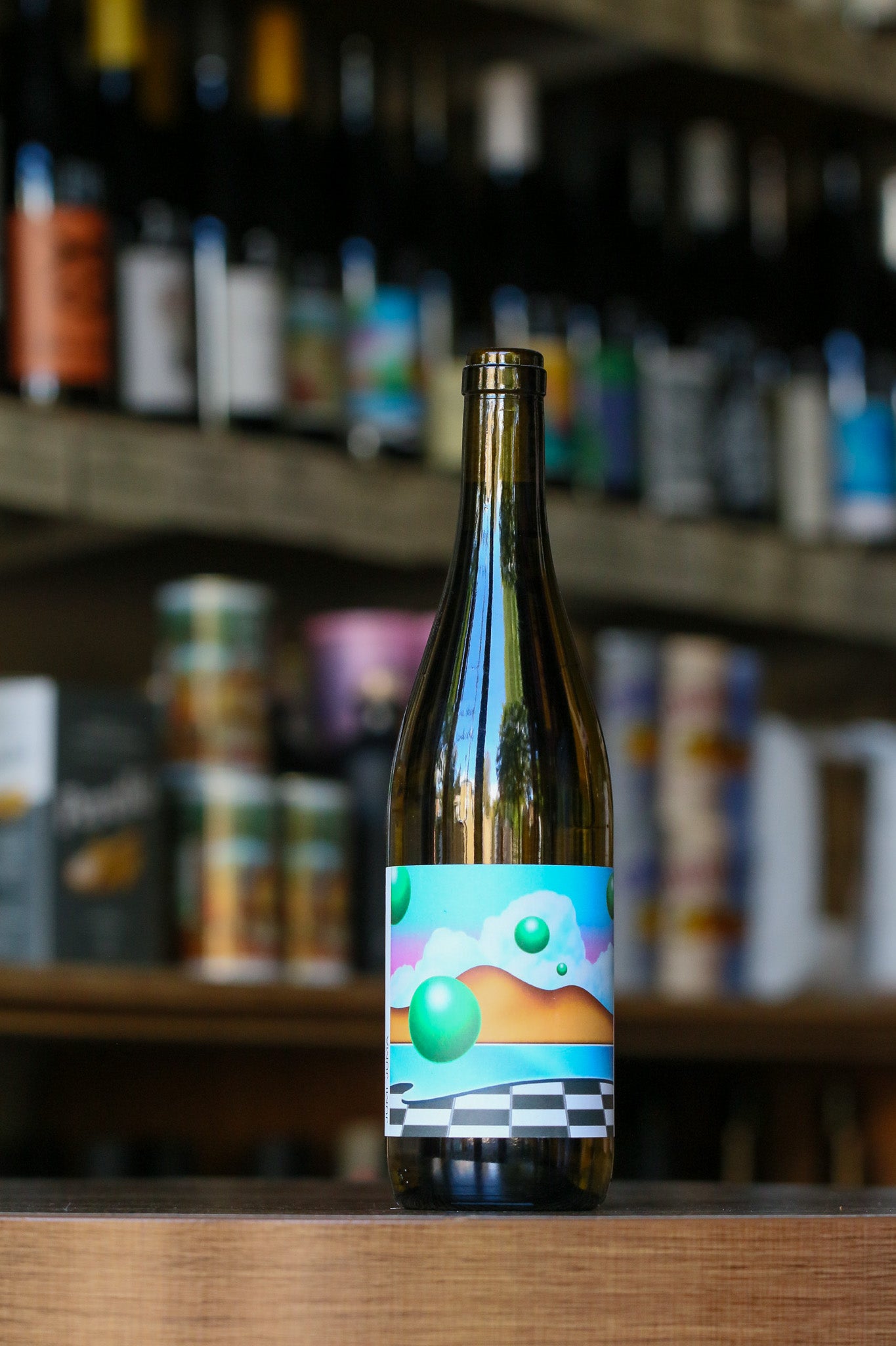 Bottle with a colorful label on a wooden surface with blurred shelves in the background